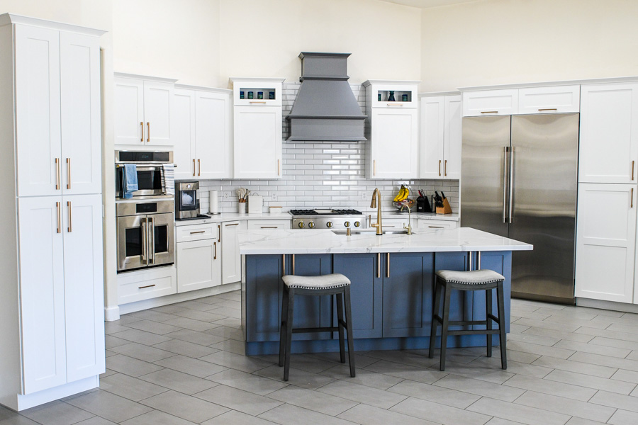 Remodeled kitchen with white shaker cabinets, a navy island, and marble waterfall counters