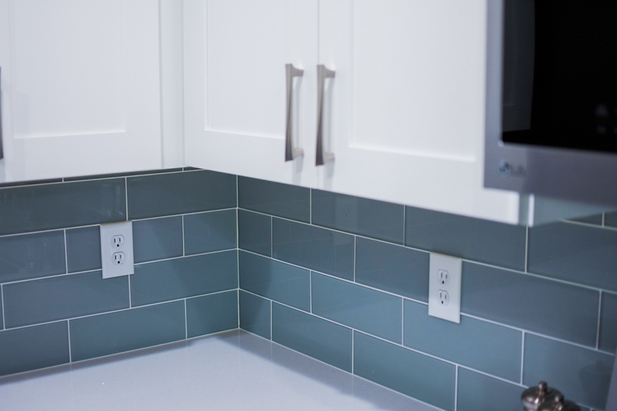 Kitchen detail with white shaker cabinets and a glass-tile backsplash